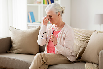 Image showing senior woman with glasses having headache at home