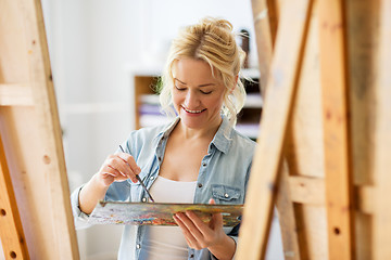 Image showing happy woman with easel painting at art school