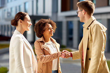 Image showing happy people shaking hands on city street