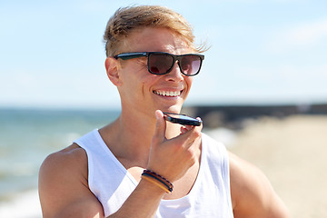 Image showing smiling man calling on smartphone on summer beach