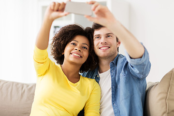 Image showing happy couple with smartphone taking selfie at home