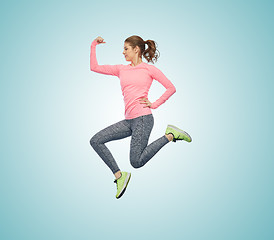 Image showing happy smiling sporty young woman jumping in air