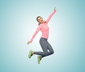 Image showing happy smiling sporty young woman jumping in air