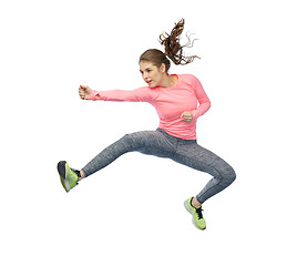 Image showing happy sporty young woman jumping in fighting pose