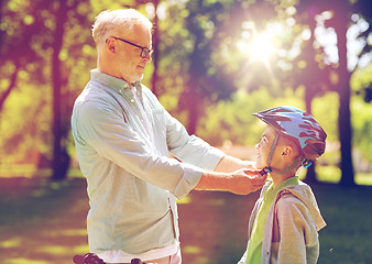 Image showing old man helping boy with bike helmet at park