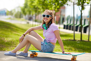 Image showing happy teenage girl with headphones and longboard