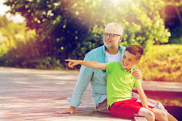 Image showing grandfather and grandson sitting on river berth