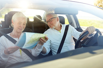 Image showing happy senior couple with map driving in car