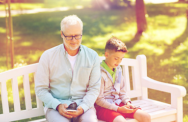 Image showing old man and boy with smartphones at summer park