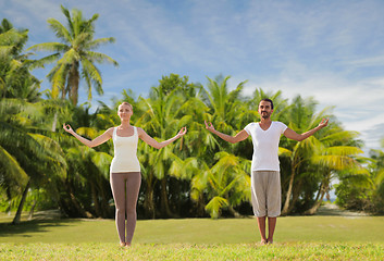 Image showing happy couple making yoga exercises on beach