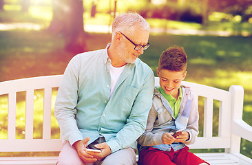 Image showing old man and boy with smartphones at summer park