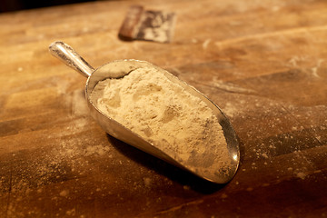 Image showing flour in bakery scoop and dough cutter on table