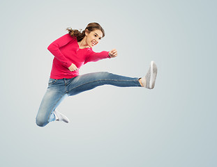 Image showing smiling young woman jumping in air