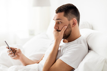 Image showing young man with smartphone in bed in morning