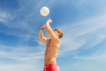 Image showing young man with ball playing volleyball on beach