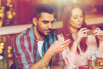 Image showing couple with smartphones dining at restaurant