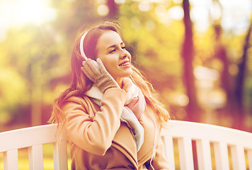 Image showing happy woman with headphones in autumn park