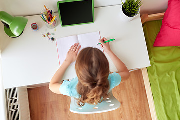 Image showing girl with tablet pc writing to notebook at home