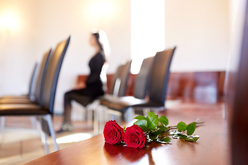 Image showing red roses and woman crying at funeral in church