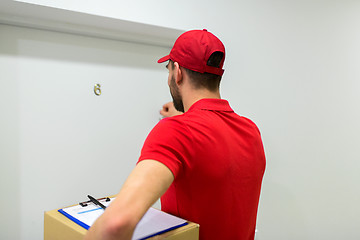 Image showing delivery man with parcel box knocking door