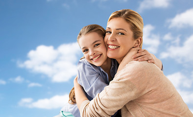 Image showing happy family of girl and mother hugging over sky