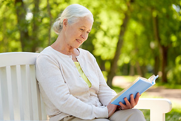 Image showing happy senior woman reading book at summer park