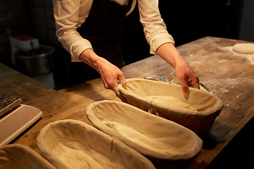 Image showing baker with dough rising in baskets at bakery