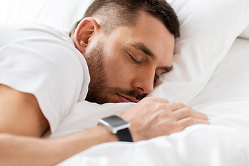 Image showing close up of man with smartwatch sleeping in bed