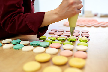 Image showing chef with injector squeezing filling to macarons