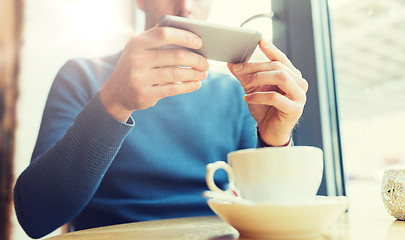 Image showing close up of man with smartphones at cafe