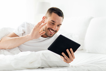 Image showing man with tablet pc having video call in bed