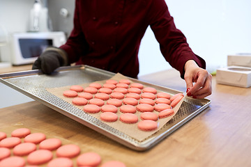 Image showing chef with macarons on oven tray at confectionery