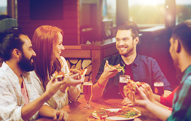 Image showing friends eating pizza with beer at restaurant