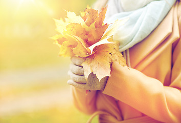 Image showing close up of woman with maple leaves in autumn park