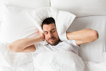 Image showing man in bed with pillow suffering from noise