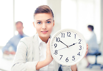 Image showing businesswoman showing white clock in office