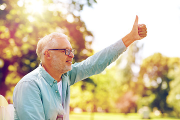 Image showing happy senior man showing thumbs up at summer park