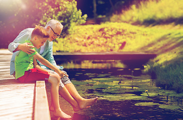 Image showing grandfather and grandson sitting on river berth