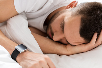 Image showing close up of man with smartwatch sleeping in bed