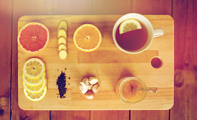 Image showing ginger tea with honey, citrus and garlic on wood