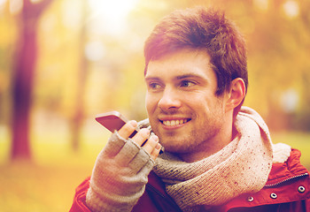 Image showing man recording voice on smartphone at autumn park