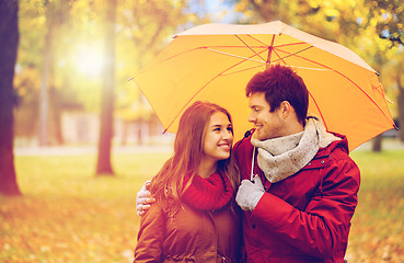 Image showing smiling couple with umbrella in autumn park