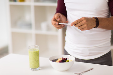 Image showing man with smartphone having breakfast at home