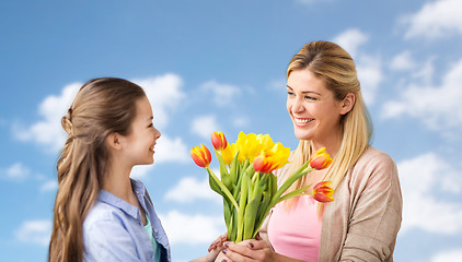 Image showing happy girl giving flowers to mother over blue sky