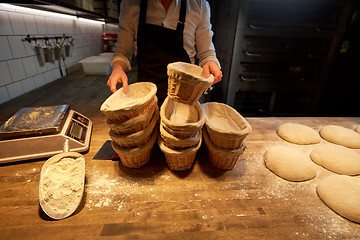 Image showing baker with baskets for dough rising at bakery