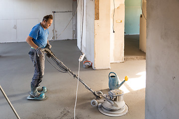 Image showing Laborer polishing sand and cement screed floor.