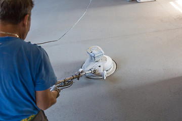 Image showing Laborer polishing sand and cement screed floor.