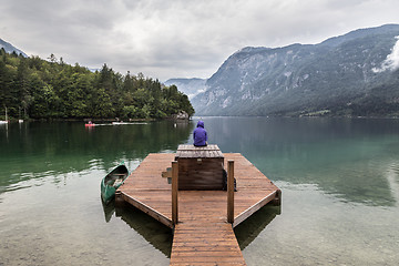 Image showing Woman wearing purple hoodie watching tranquil overcast morning scene at lake Bohinj, Alps mountains, Slovenia.