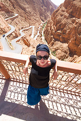 Image showing Image of female tourist relaxing on a terrace ovelooking winding road in Dades Valley, Atlas mountains, Morocco.