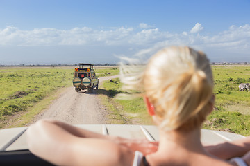 Image showing Woman on african wildlife safari observing nature from open roof safari jeep.